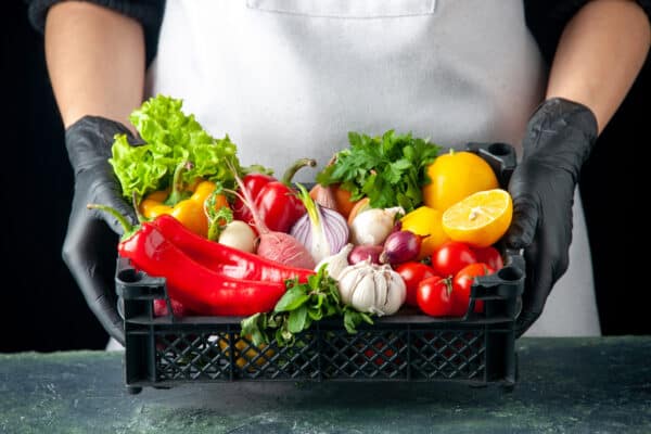 Manos con caja de verduras