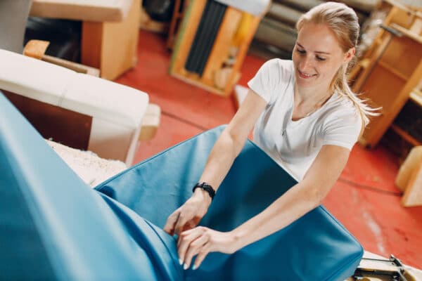 mujer tapizando sillón de cuero azul