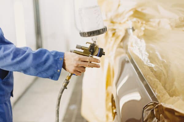 mano con aerógrafo pintando coche